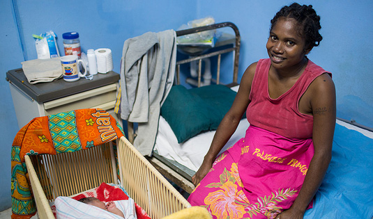 A Vanuatu mother watches over her newborn daughter. (Photo by Connor Ashleigh for AusAID)