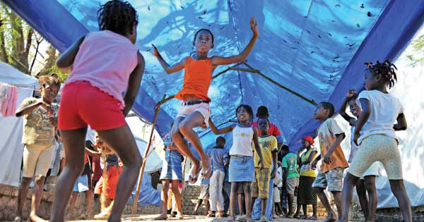 A month after the 7.0 magnitude earthquake in 2010, Pétionville children jump rope under a sheltering tarp. (U.S. Navy/Spike Call)