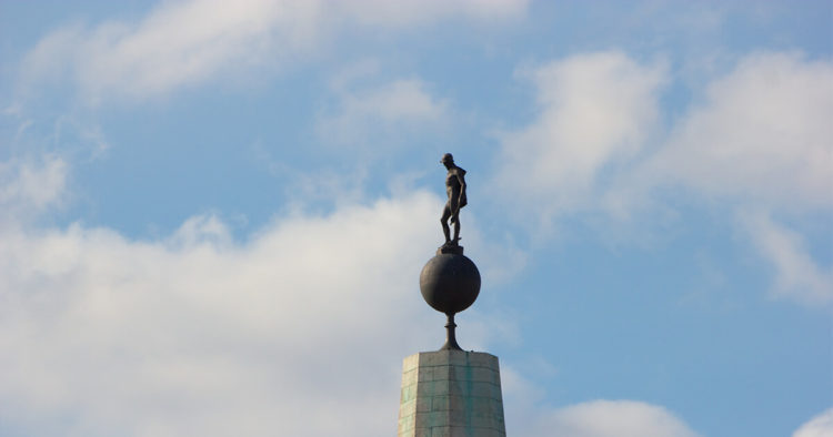 A picture of a statue of a man standing on a globe