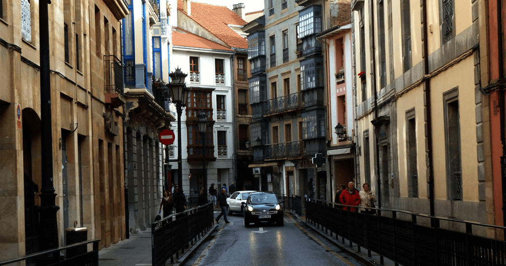 A small car navigates the narrow lanes of a Spanish city