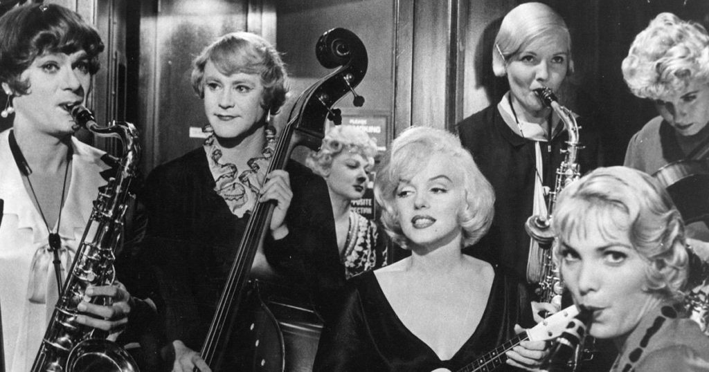 Black-and-white photo of the "Running Wild" scene from Some Like it Hot. Cast members, including Jack Lemmon, Tony Curtis, and Marilyn Monroe, play various instruments in the photo.