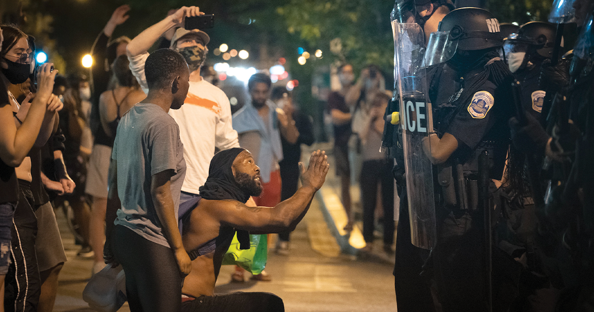 A man kneels before police on May 30, 2020, during a protest of George Floyd’s murder that took place in Washington, D.C., not far from the White House. (Jay Mallin/ZUMA Wire)