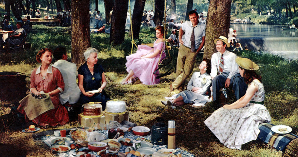 From left to right, Betty Field, Cliff Robertson, Verna Felton, Kim Novak, William Holden, Rosalind Russell, Arthur O'Connell, and Susan Strasberg in 1955's <em>Picnic</em> (Ronald Grant Archive/Everett Collection)