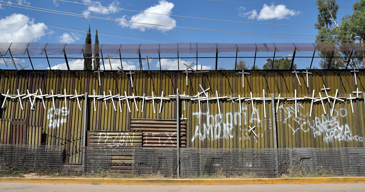 White crosses with the names of those who have died crossing the U.S. border adorn the Mexican side of the border wall in Heroica Nogales, Mexico (Flickr/jonathanmcintosh)
