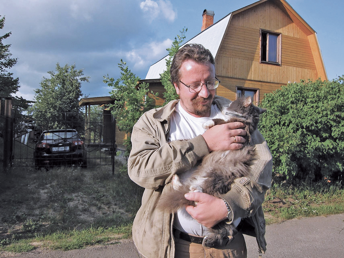 The author’s father, Dmitry, with his cat Stilianos, in front of the family’s dacha in 2011. (Courtesy of the author)